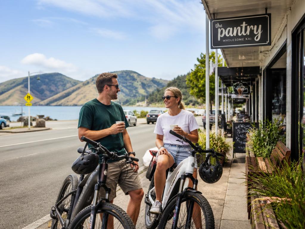 Two riders with e-bikes stopped at a seaside town cafe